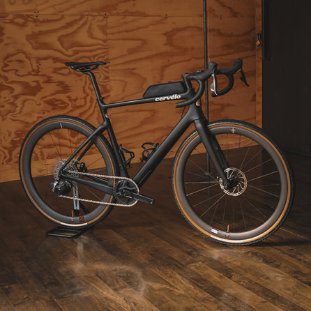 A Cervelo Aspero with SRAM Rival AXS in Five Black in a plywood room