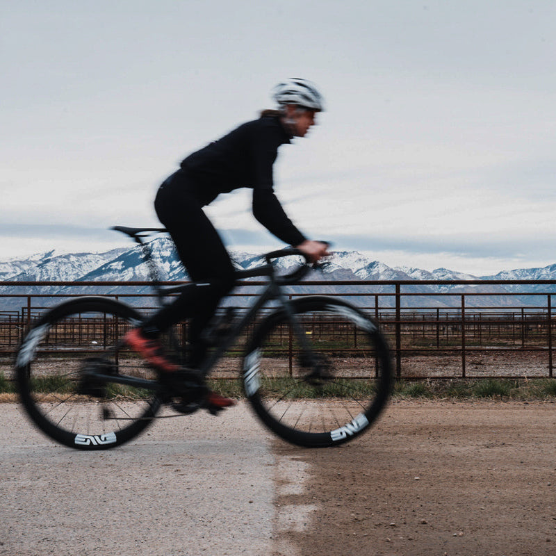 A blurry image of a woman riding a bike with Enve AR40 wheels on a dirt road