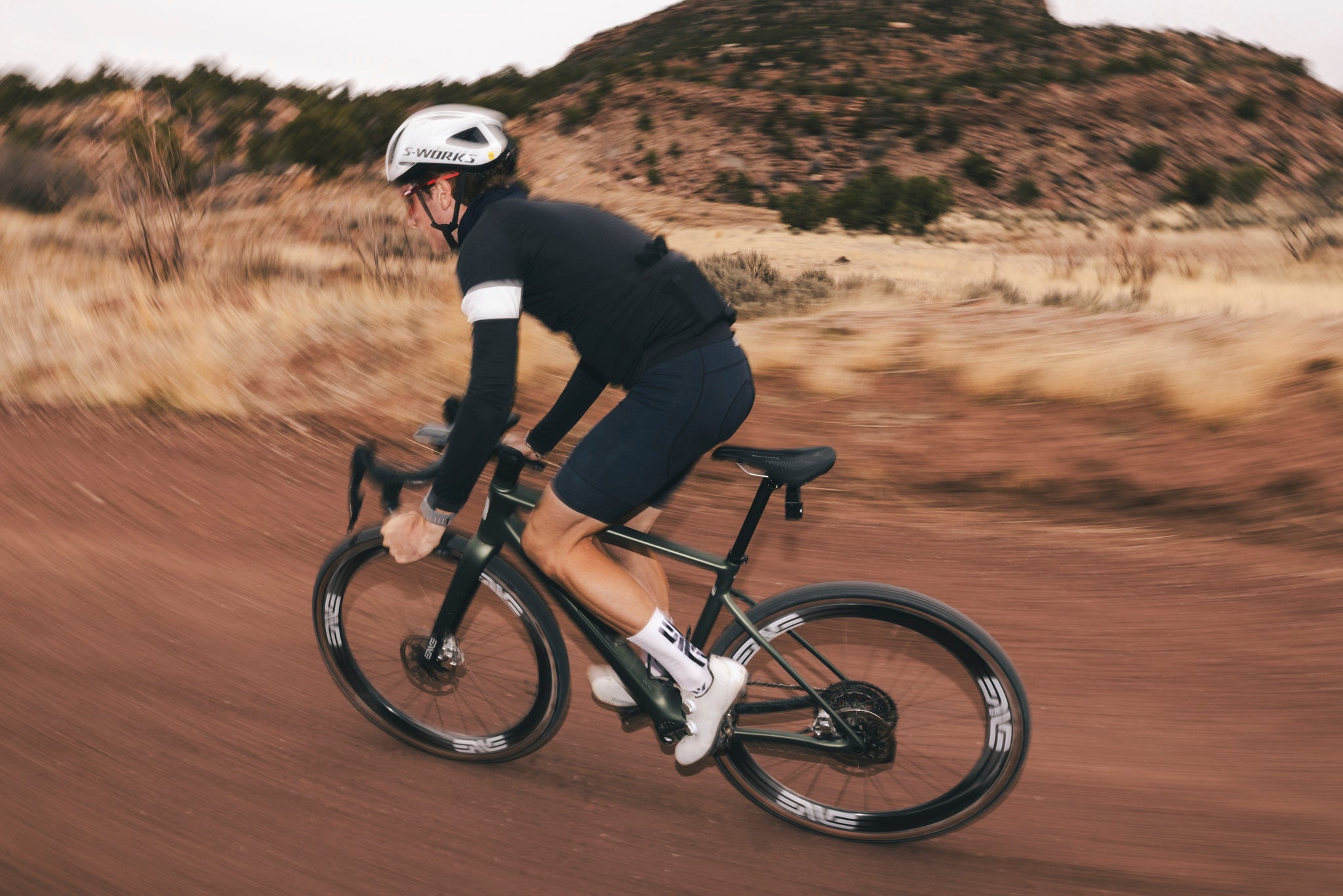 A cyclist riding a green ENVE MOG on a dirt road in the desert