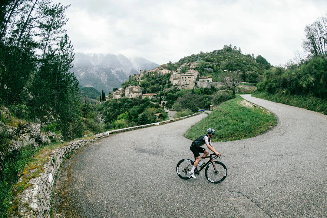 Cyclist riding an Enve Melee on a winding road with mountains in the background