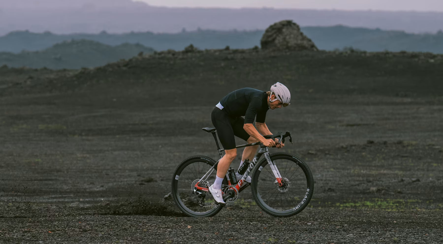 A cyclist riding a Factor Aluto gravel bike in Quattro Grey off road