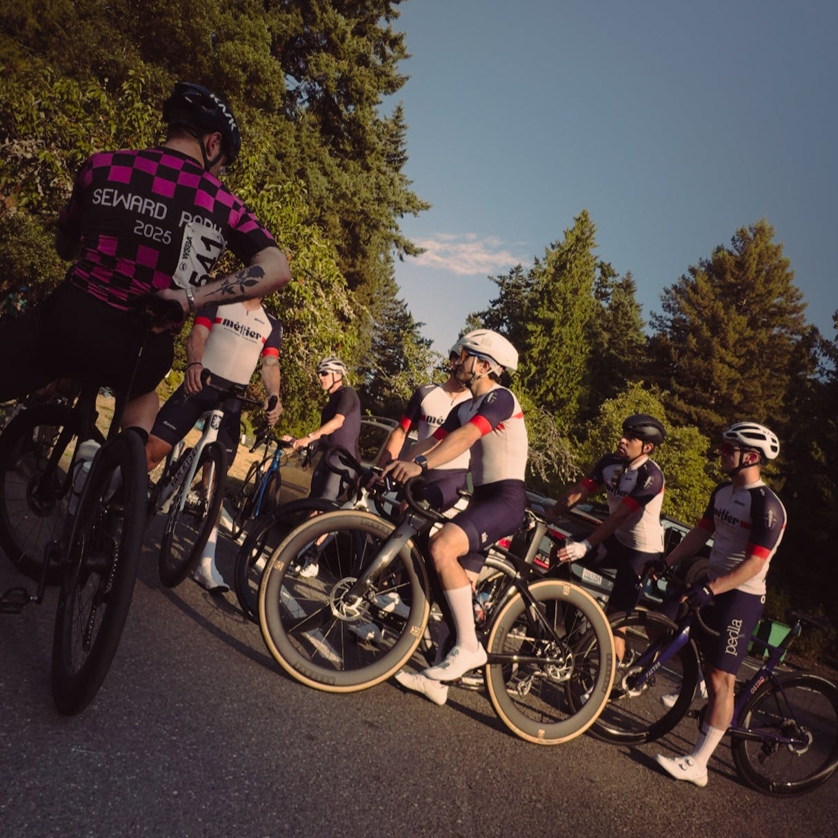 Group of Metier Club cyclists at Seward Park with trees in the background