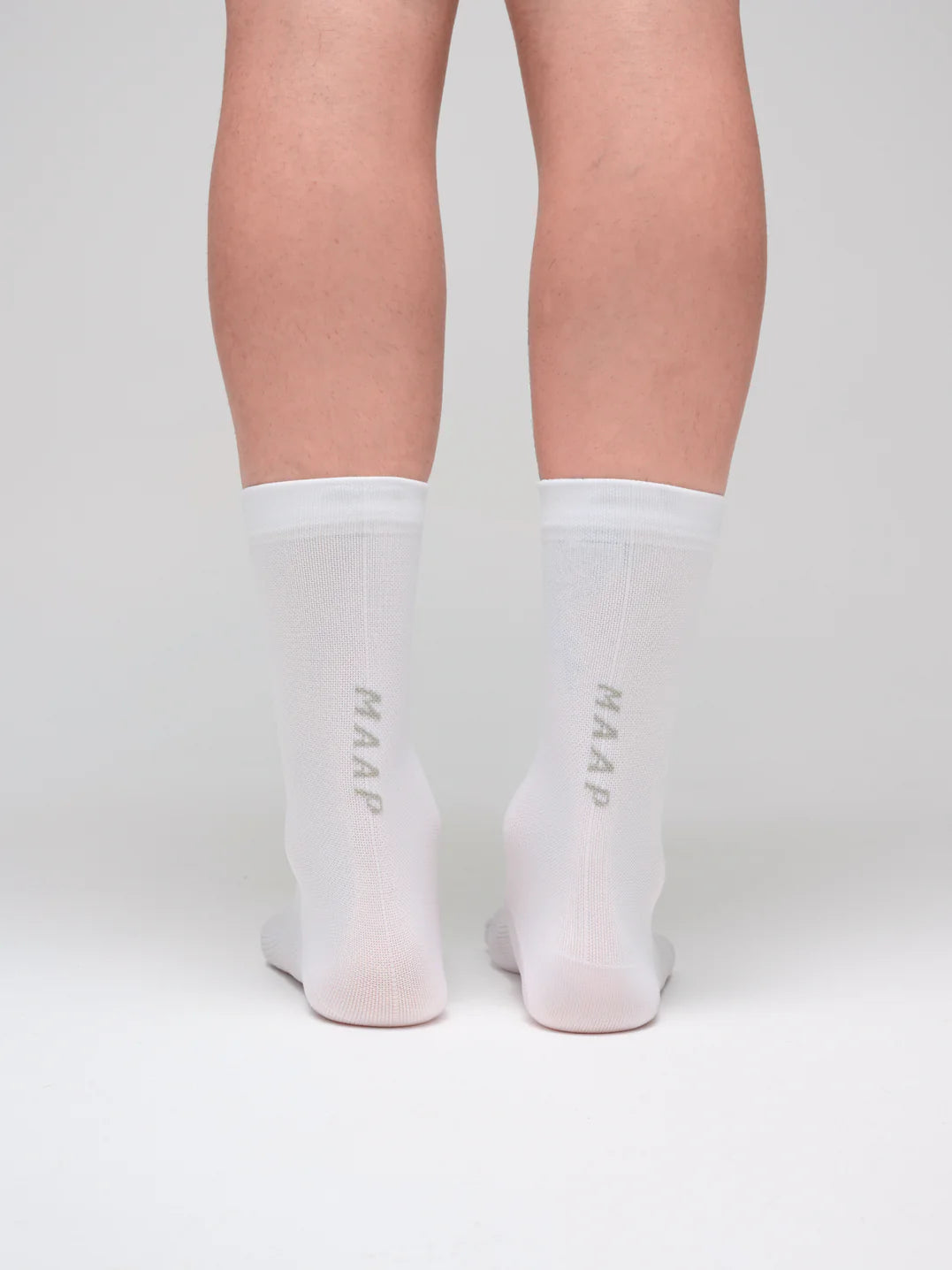 White MAAP Team socks with 'MAAP' branding worn by a female cyclist with a white background