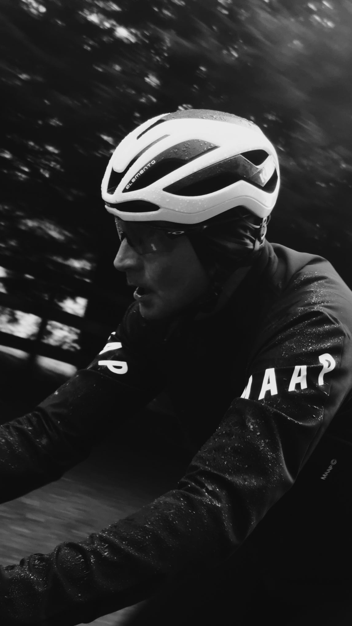 A cyclist riding their bike in the rain, with water droplets accumulating on the sleeves of their MAAP Elements Pro Race Jacket