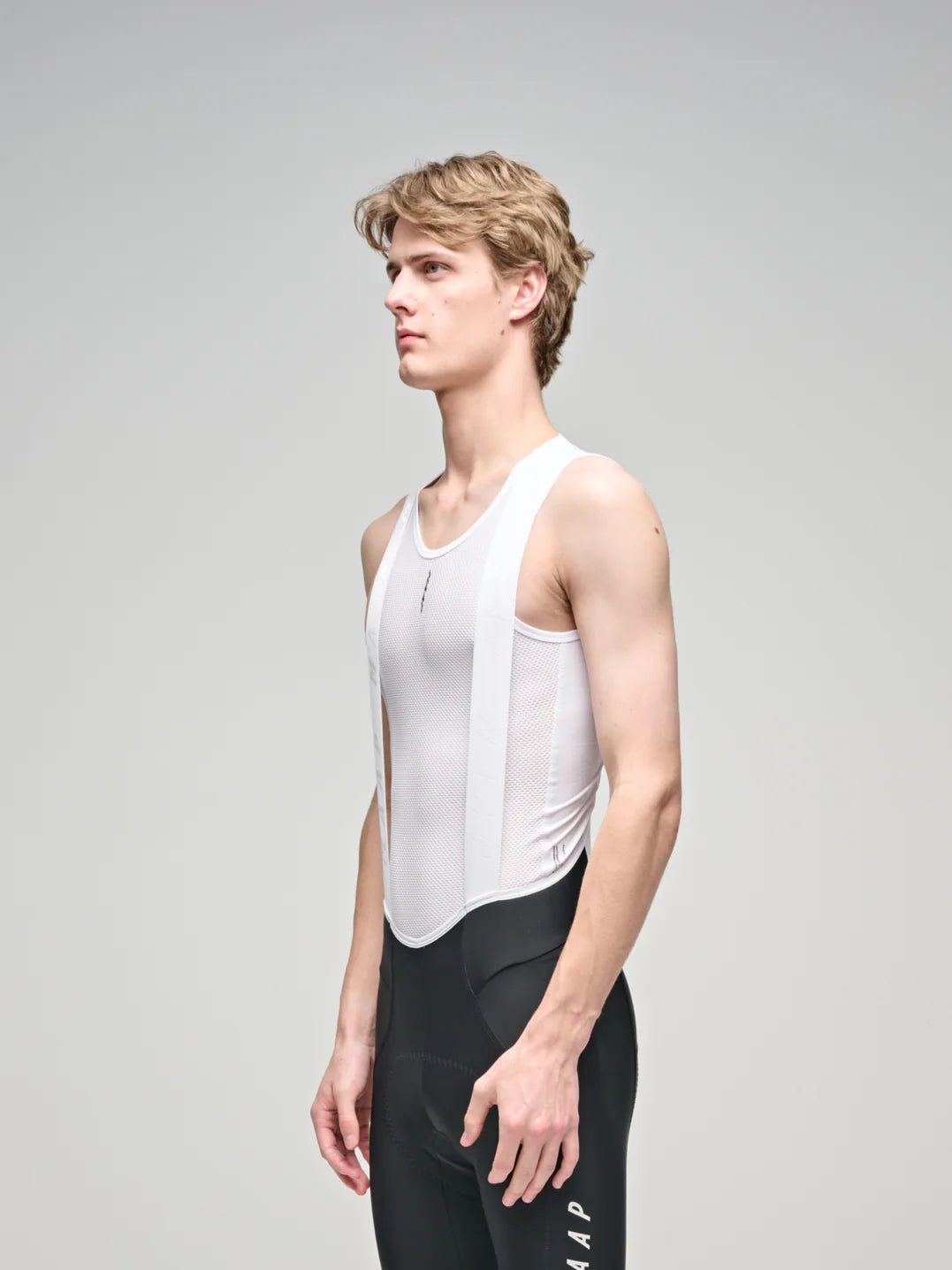 The upper half of a male cyclist wearing a MAAP Team Mesh base layer in White in front of a white background