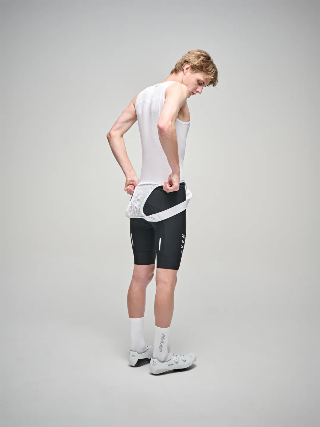 The back of a male cyclist wearing a MAAP Team mesh base layer in white on a white background