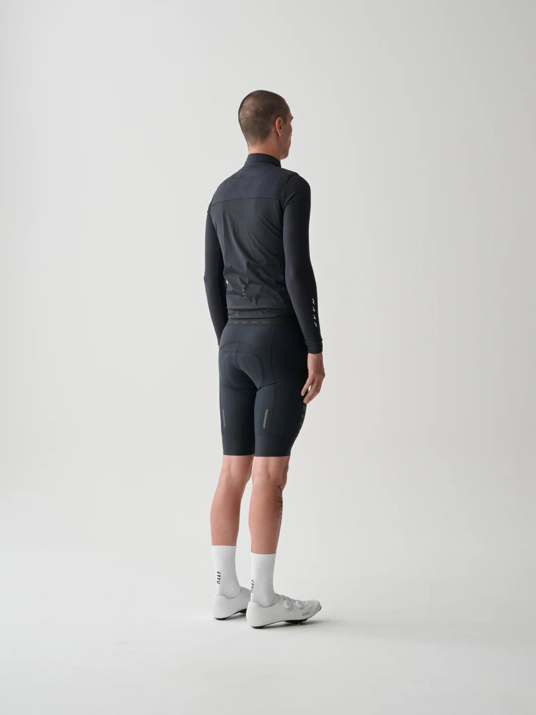 The back of a male cyclist wearing a MAAP Flow Vest in Black with a white background