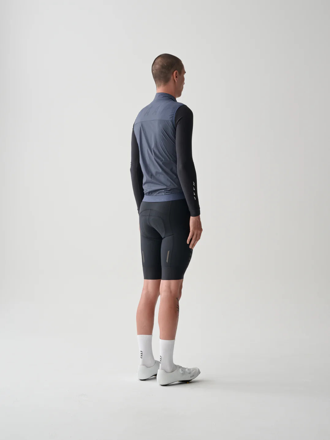 The back of a male cyclist wearing a MAAP Flow Vest in midnight blue with a white background