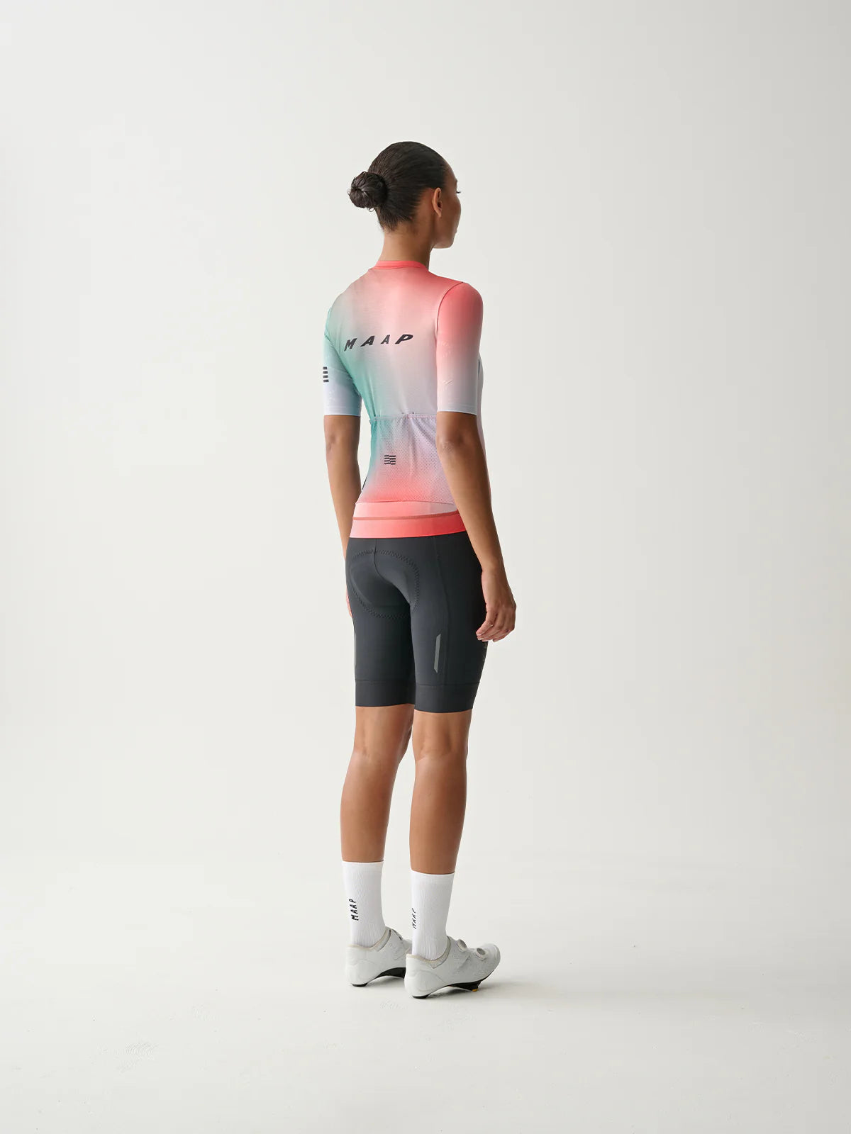 A female cyclist wearing a MAAP Women's Blurred Out 2.0 Pro Hex Short Sleeve Jersey in Red Mix