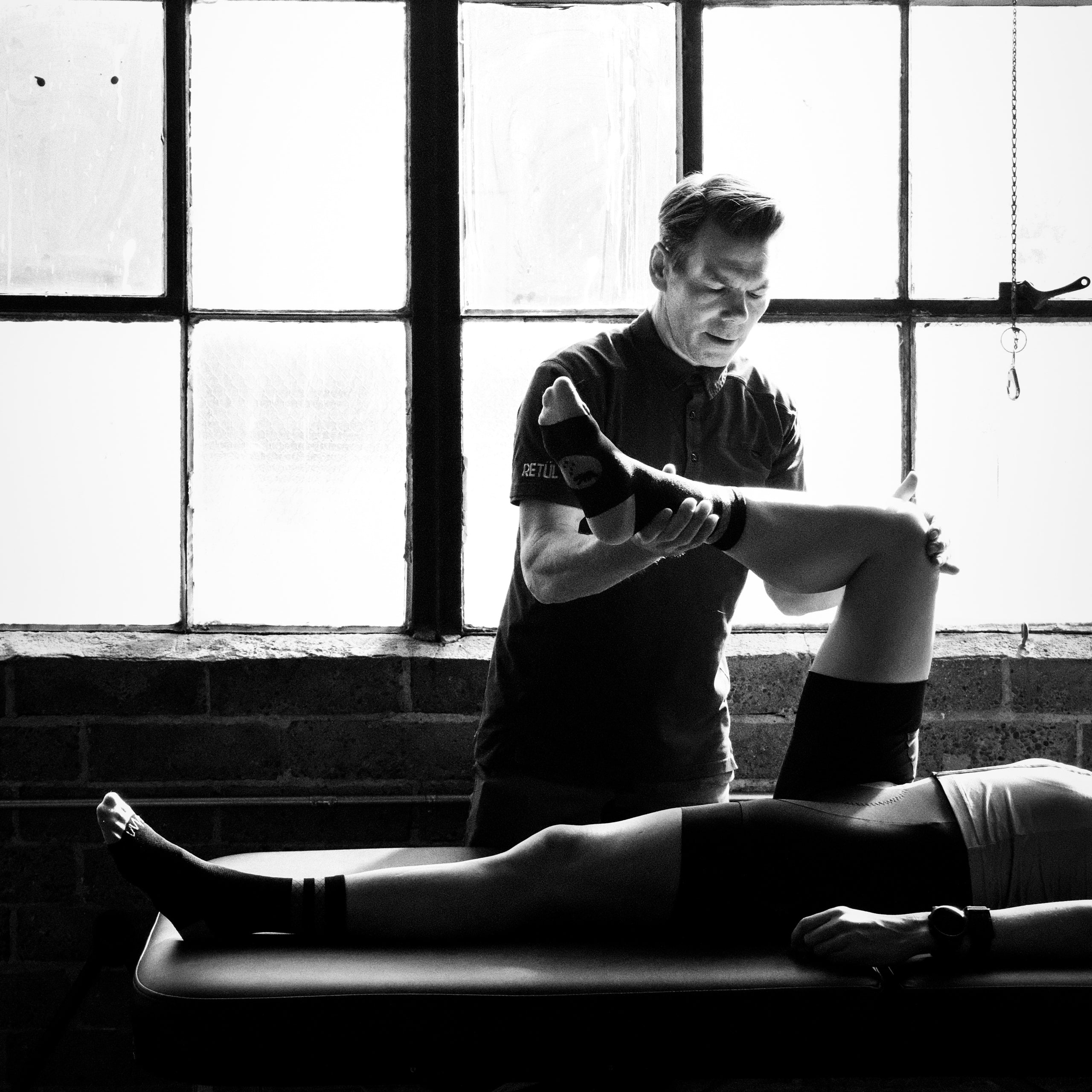 Pro bike fitter Todd Herriott checks hip interal rotation of a client during a Premium bike fit with a female cyclist at Metier Seattle in the bike fit studio