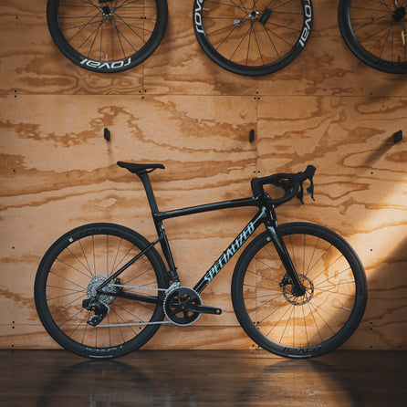 A Specialized SL8 Tarmac with SRAM Rival AXS Groupset leaning against a plywood wall at Metier Racing & Coffee