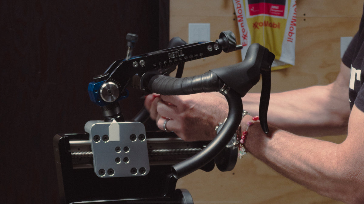 A close up of a bike fitter adjusting bar reach on a Retul Bike
