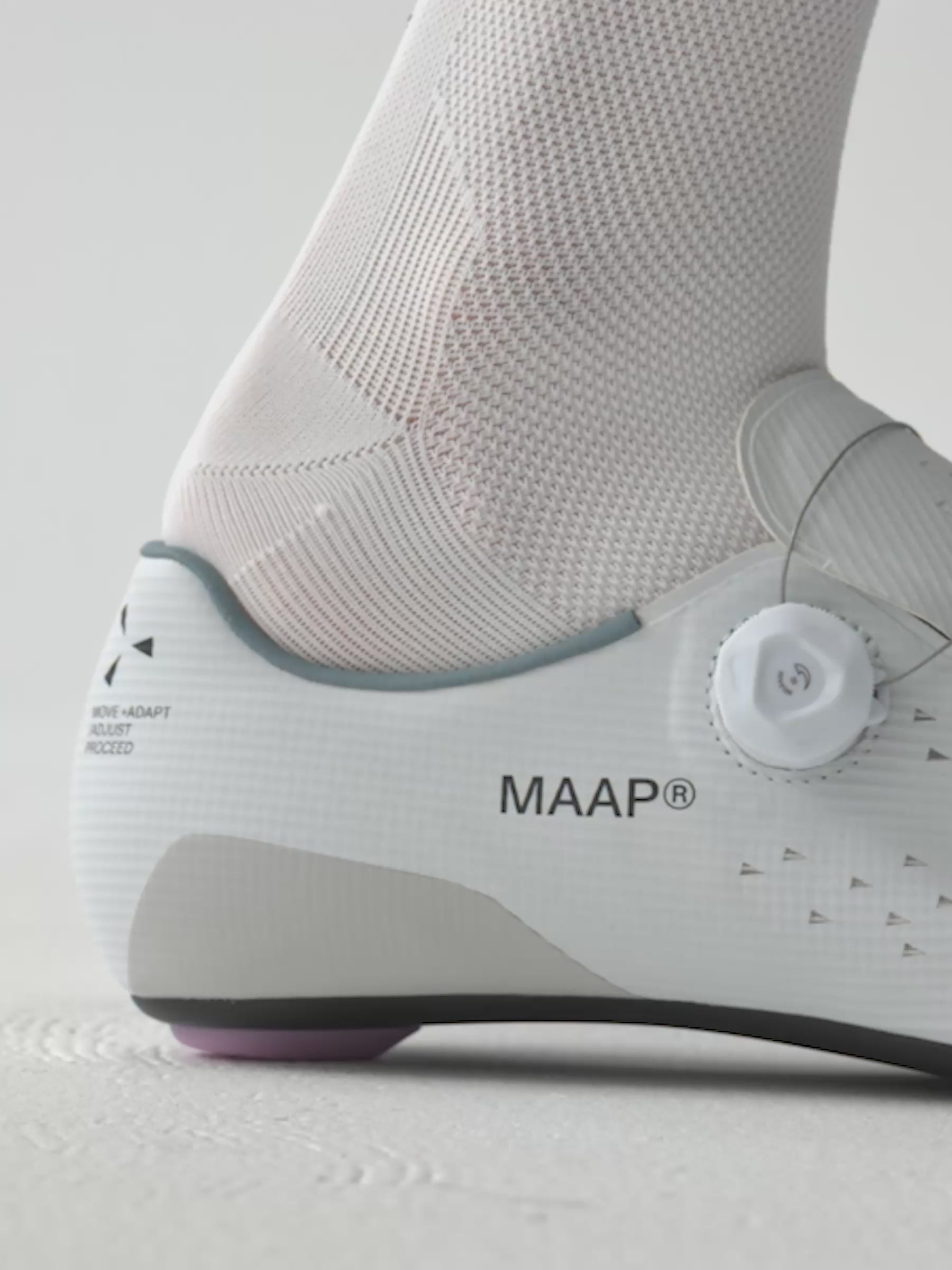 A detail shot of a model sliding their foot into a MAAP x QUOC M3 carbon road cycling shoe